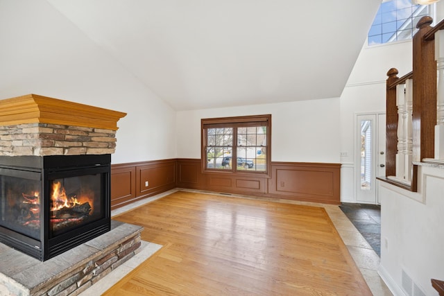 unfurnished living room with light hardwood / wood-style flooring, a fireplace, and high vaulted ceiling