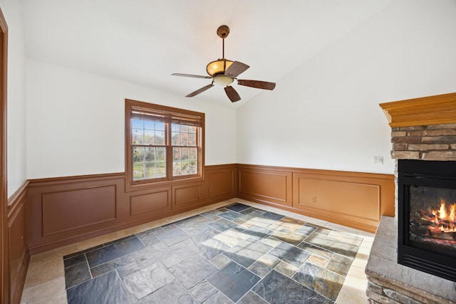 interior space with vaulted ceiling, a fireplace, and ceiling fan