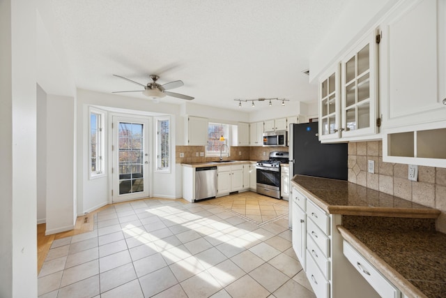 kitchen with white cabinets, tasteful backsplash, ceiling fan, light tile patterned flooring, and stainless steel appliances