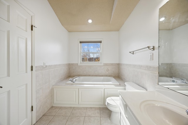 bathroom featuring a washtub, toilet, tile patterned floors, tile walls, and vanity