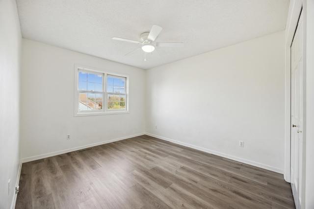 unfurnished room with a textured ceiling, ceiling fan, and dark hardwood / wood-style flooring