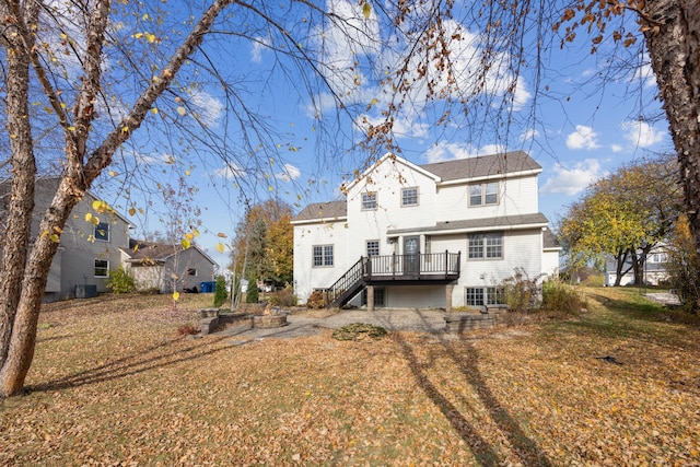 rear view of property featuring cooling unit, a deck, and a lawn