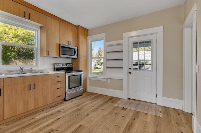 kitchen featuring appliances with stainless steel finishes, sink, light brown cabinets, and light hardwood / wood-style floors