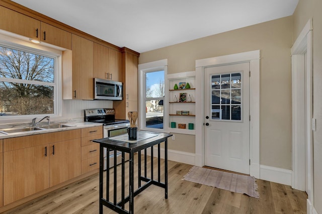 kitchen with light brown cabinetry, sink, light hardwood / wood-style flooring, and appliances with stainless steel finishes