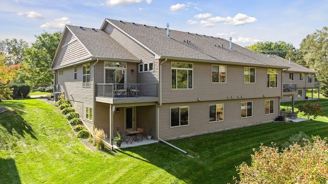 rear view of house featuring a shingled roof, a patio area, and a yard