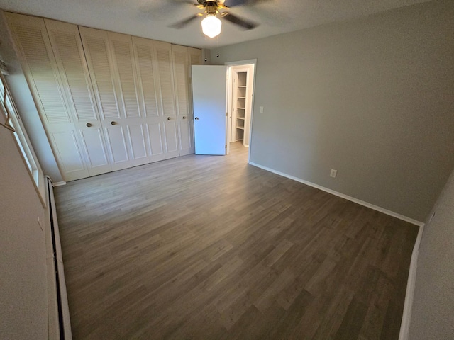 unfurnished bedroom with dark wood-type flooring, ceiling fan, and a closet