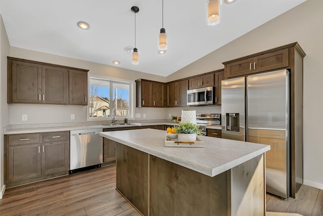 kitchen with appliances with stainless steel finishes, vaulted ceiling, hardwood / wood-style floors, and hanging light fixtures