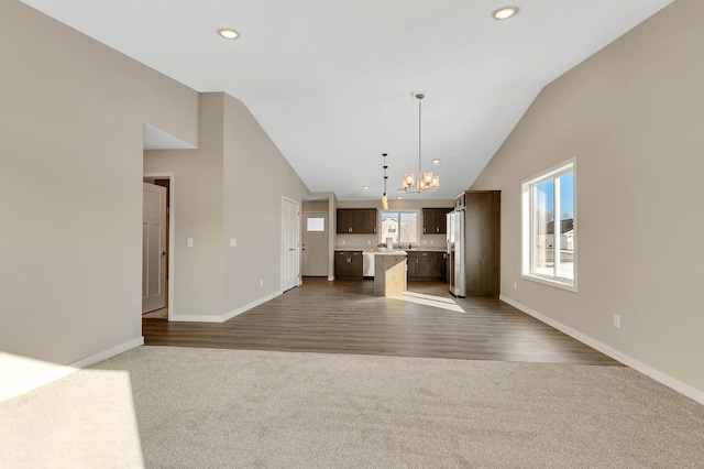 1710 Maple Leaf Ln, Litchfield, MN 55355 - unfurnished living room featuring vaulted ceiling, an inviting chandelier, baseboards, and dark carpet