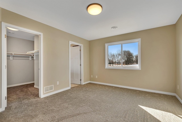 unfurnished bedroom featuring a closet, a spacious closet, and carpet