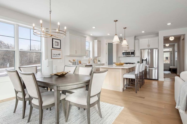 dining room featuring light hardwood / wood-style floors, sink, and an inviting chandelier