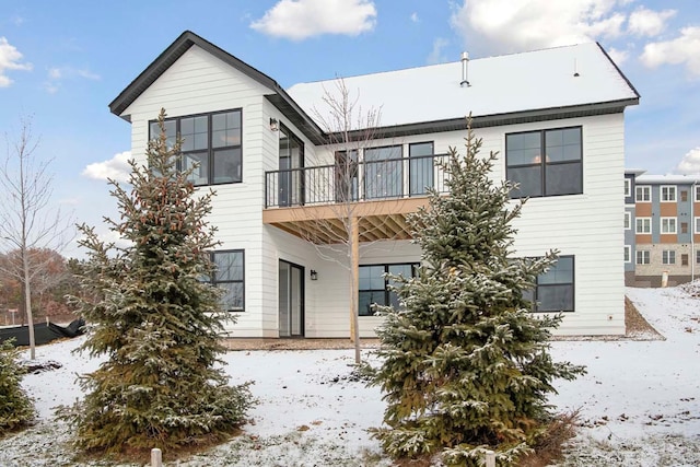 snow covered rear of property with a balcony