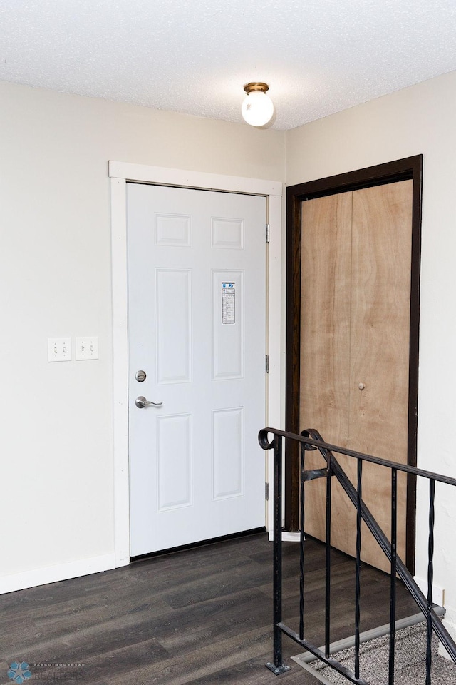 foyer entrance with a textured ceiling and dark wood-type flooring