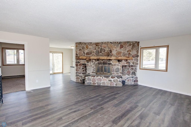 unfurnished living room featuring a textured ceiling, baseboards, wood finished floors, a fireplace, and a baseboard radiator