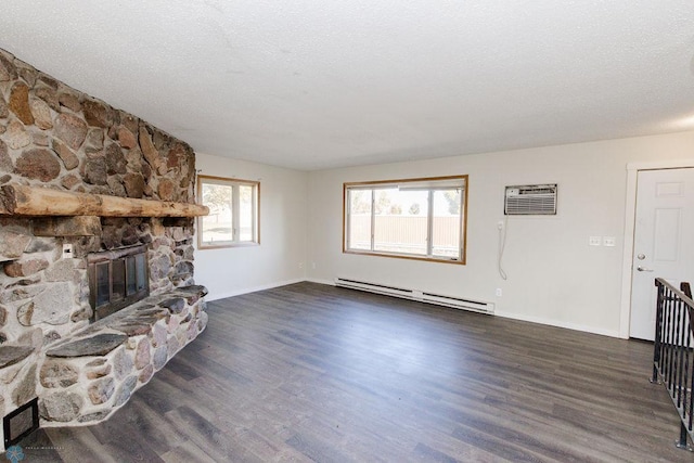 living room with dark wood-type flooring, a stone fireplace, a baseboard heating unit, an AC wall unit, and a textured ceiling