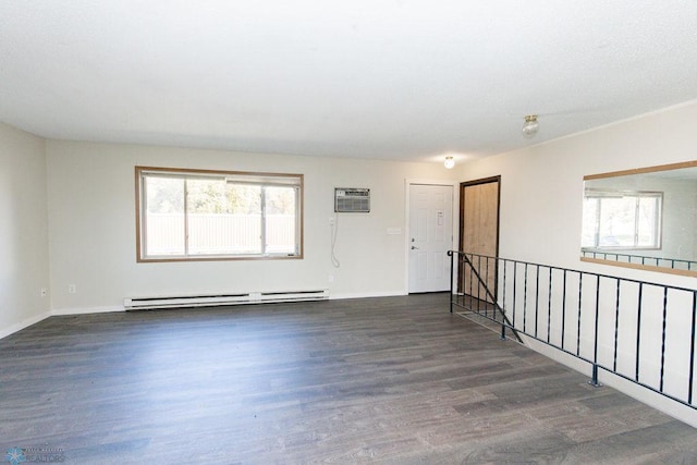 empty room with a wall mounted AC, a healthy amount of sunlight, dark hardwood / wood-style flooring, and a baseboard radiator