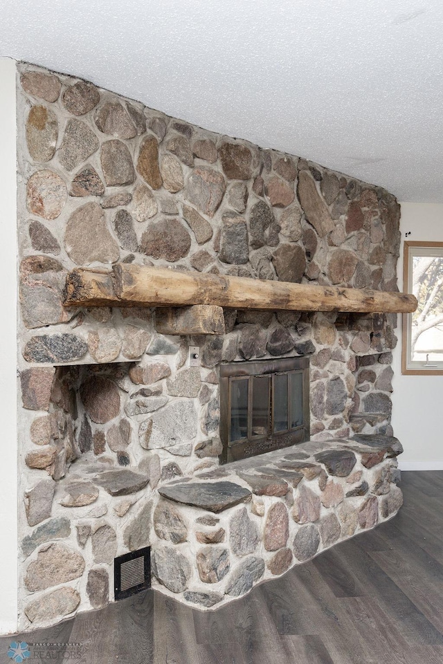 room details featuring hardwood / wood-style floors, a stone fireplace, and a textured ceiling