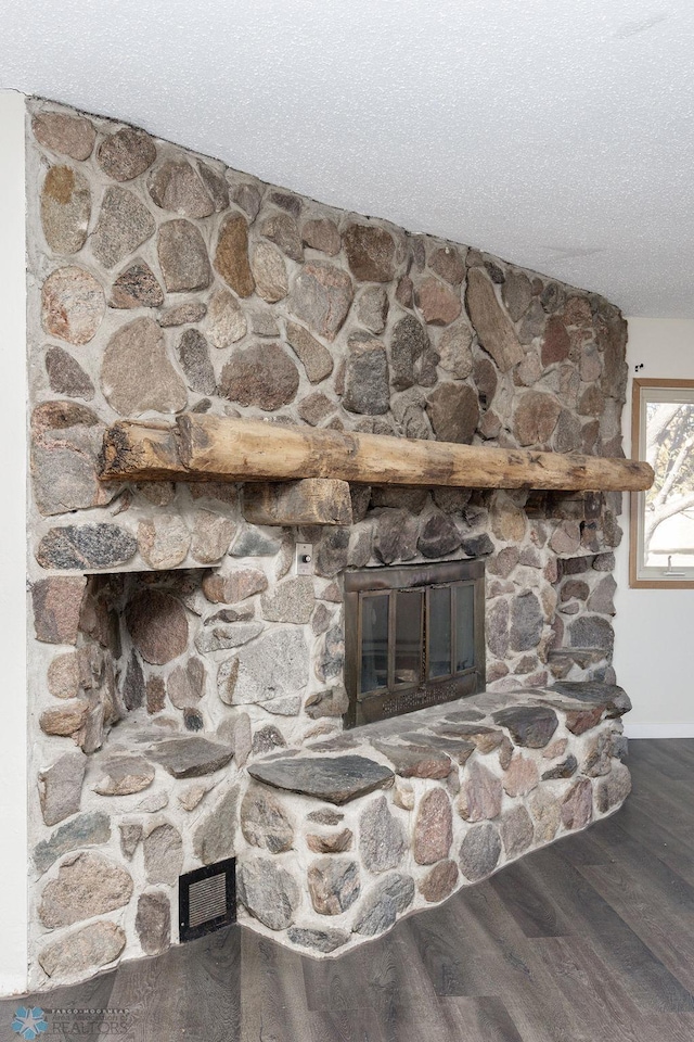 details with baseboards, wood finished floors, and a stone fireplace