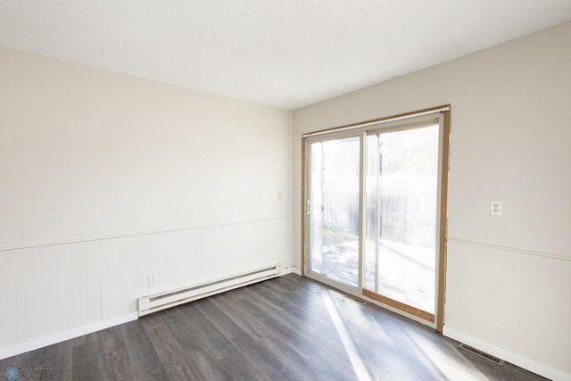 empty room featuring visible vents, a wainscoted wall, wood finished floors, and a baseboard radiator