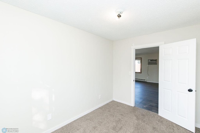 carpeted empty room with a textured ceiling, baseboard heating, and a wall unit AC