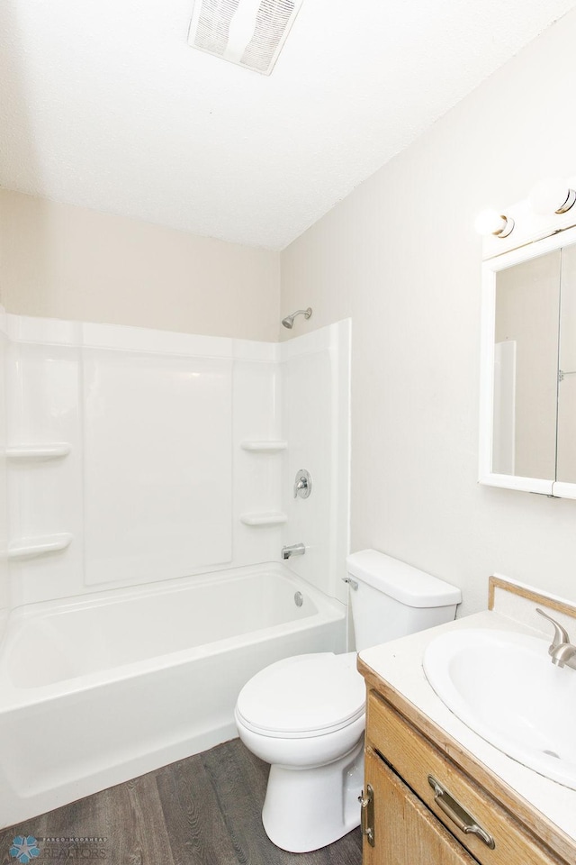 full bathroom with toilet, visible vents, wood finished floors, vanity, and shower / tub combination