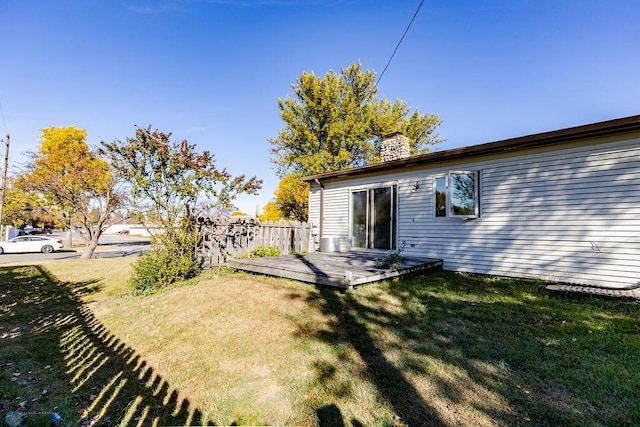 rear view of house featuring fence, a chimney, a yard, and a deck