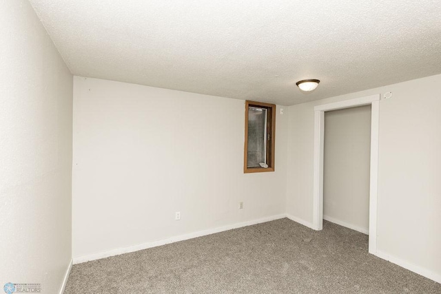 carpeted empty room featuring a textured ceiling