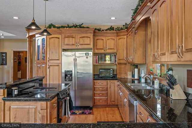 kitchen with stainless steel appliances, sink, pendant lighting, a textured ceiling, and light hardwood / wood-style floors