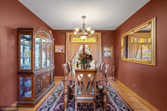 dining space featuring light hardwood / wood-style floors, a notable chandelier, and a textured ceiling