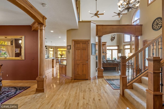 entryway featuring light wood-type flooring, plenty of natural light, and decorative columns