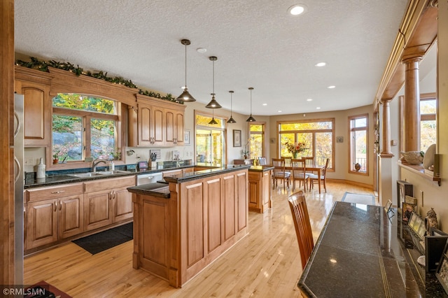 kitchen with light hardwood / wood-style flooring, ornate columns, a center island, and plenty of natural light