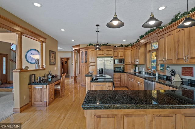 kitchen featuring decorative columns, stainless steel appliances, sink, light hardwood / wood-style floors, and decorative light fixtures