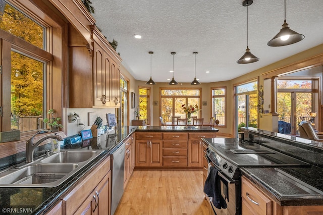 kitchen featuring light wood-type flooring, a textured ceiling, decorative light fixtures, and a healthy amount of sunlight