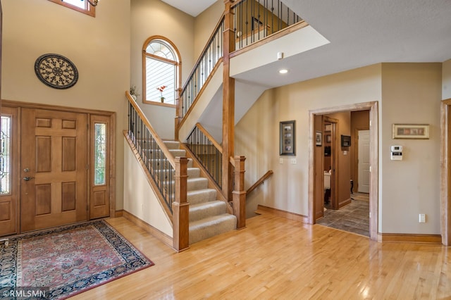 entrance foyer with hardwood / wood-style floors, a high ceiling, and plenty of natural light