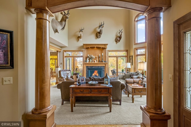 living room featuring carpet, ornate columns, a towering ceiling, and plenty of natural light