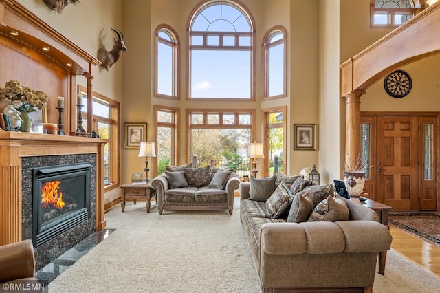 living room featuring a towering ceiling, ornate columns, hardwood / wood-style floors, and plenty of natural light