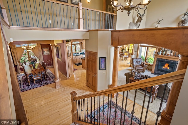 stairway with a towering ceiling, hardwood / wood-style flooring, and decorative columns