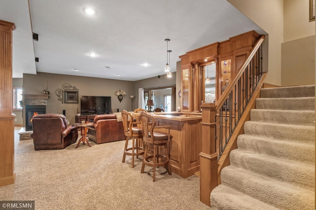 kitchen featuring a kitchen bar, hanging light fixtures, light colored carpet, and kitchen peninsula