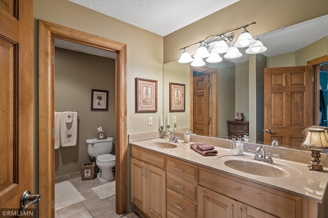 bathroom featuring toilet, a textured ceiling, vanity, and tile patterned flooring