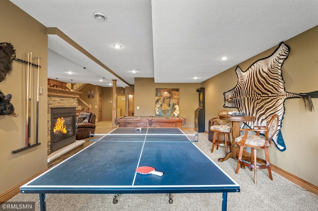 playroom with a stone fireplace, a textured ceiling, and carpet flooring