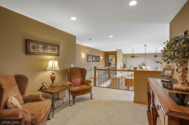 sitting room with light carpet, a textured ceiling, and ceiling fan