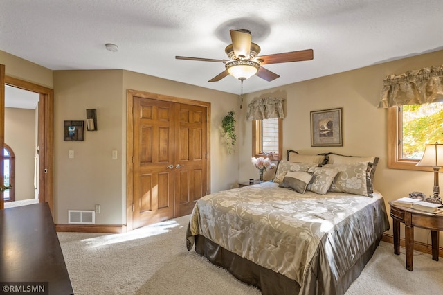 carpeted bedroom with a textured ceiling, a closet, and ceiling fan