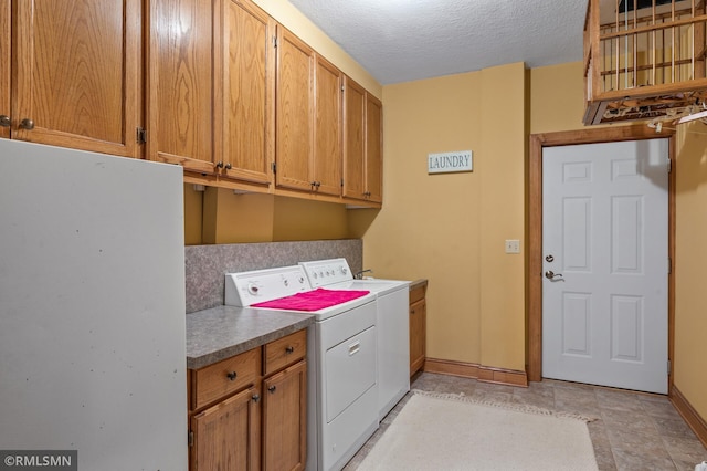 clothes washing area featuring cabinets, a textured ceiling, and washer and clothes dryer