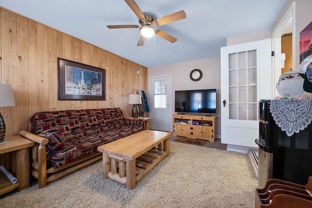 carpeted living room with wooden walls, a textured ceiling, and ceiling fan