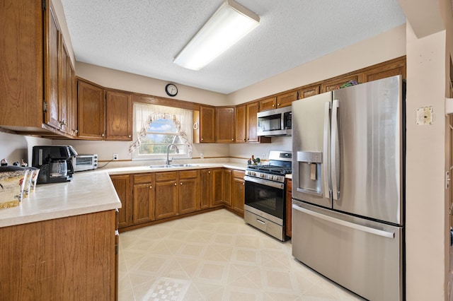 kitchen with sink, appliances with stainless steel finishes, and a textured ceiling