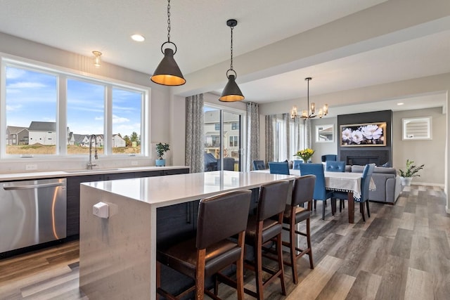 kitchen with hanging light fixtures, dishwasher, a kitchen island, and hardwood / wood-style floors