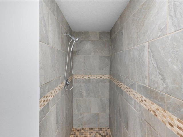 bathroom with a tile shower and a textured ceiling