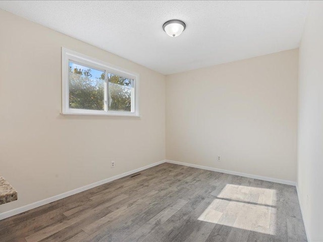 unfurnished room featuring a textured ceiling and light wood-type flooring