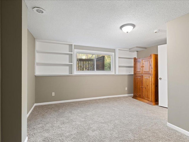 carpeted empty room featuring a textured ceiling