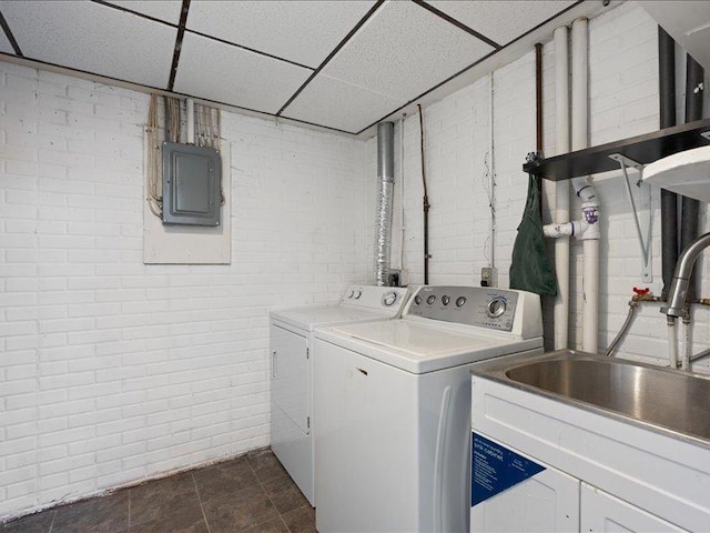 laundry room with electric panel, sink, brick wall, and washing machine and clothes dryer