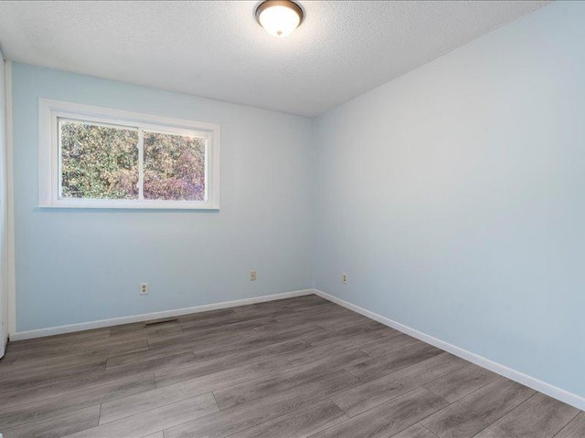 spare room featuring wood-type flooring and a textured ceiling